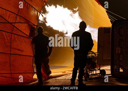 Deux hommes en silhouette gonflant une montgolfière pour une balade en Cappadoce. Banque D'Images