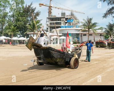 Pêcheurs à Sam son Beach, Thanh Hoa, Vietnam tirant leur bateau sur la plage à la fin de la journée de travail. Le bateau est construit en bois, mais couvert Banque D'Images