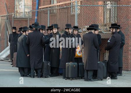 Un groupe d'étudiants juifs orthodoxes attendent un bus pour les transporter à une classe de Talmud de l'autre côté de Brooklyn, New York. Banque D'Images