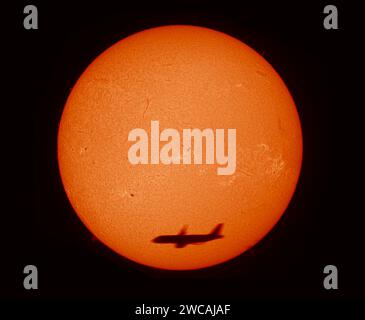 Londres, Royaume-Uni. 15 janvier 2024. Un avion de ligne de haute altitude qui passe se détache contre le Soleil, qui montre une surface active avec 12 groupes de taches solaires aujourd'hui, 15 janvier, dont un point mort et face à la Terre. Image photographiée à travers un télescope avec filtre solaire alpha hydrogène qui affiche les détails de surface sur la photosphère. Crédit : Malcolm Park/Alamy Live News Banque D'Images