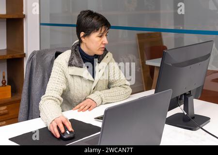 Femme caucasienne concentrée travaillant dans le bureau devant l'ordinateur Banque D'Images
