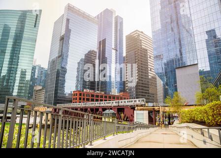 Chemin déserté de la rive dans le centre-ville de Chicago avec des tours de bureau modernes en verre en arrière-plan. Un train surélevé traverse un pont. Banque D'Images