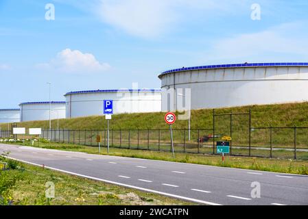 Terminal pétrolier clôturé avec de grands réservoirs pour le stockage de pétrole brut dans un port par une journée ensoleillée d'été Banque D'Images