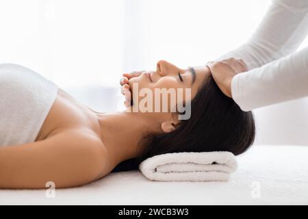Thérapeute spa faisant massage relaxant de la tête pour jeune dame indienne Banque D'Images