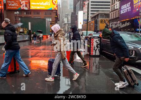 Les touristes avec leurs valises roulantes schlep sous la pluie et le grésil à Times Square à New York le dimanche 7 janvier 2024. (© Richard B. Levine) Banque D'Images