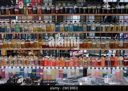 Bouteilles colorées de parfums faits main, d'huiles essentielles et de mélanges de beauté exposées en rangées dans un stand de vendeur extérieur. Banque D'Images