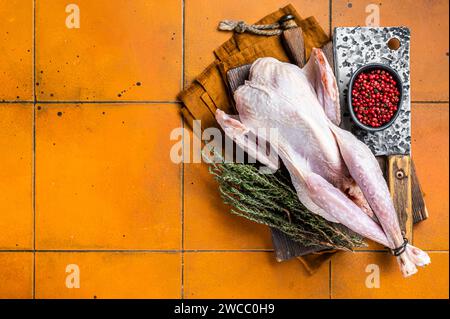 Ferme Raw Guineafowl, pintade aux herbes prêtes à cuire. Fond orange. Vue de dessus. Espace de copie. Banque D'Images