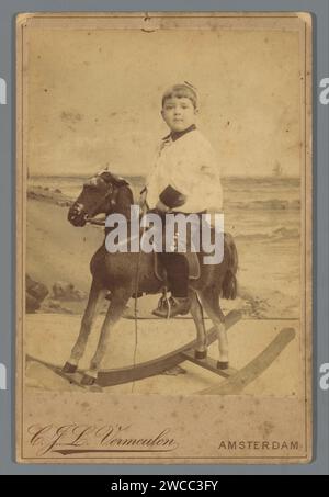 Portrait d'un garçon inconnu sur un cheval à bascule, Cornelis Johannes Lodewicus Vermeulen, v. 1888 - v. 1896 photographie. Support photographique de cabinet Amsterdam. cheval à bascule imprimé blanc sur carton. garçon (enfant entre tout-petit et jeune) Banque D'Images