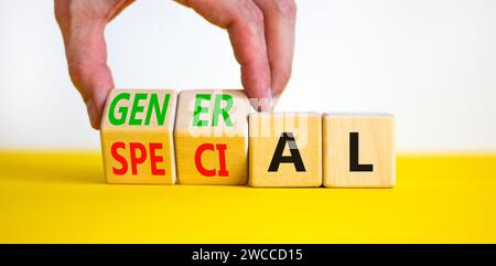 Symbole général ou spécial. Homme d'affaires tourne de beaux cubes en bois et change le mot spécial en général. Belle table jaune fond blanc. Banque D'Images