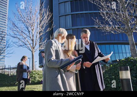 Trois hommes d'affaires à l'extérieur de l'immeuble de bureaux avec des documents discutant des plans, homme d'affaires et femmes d'affaires s'amusant bavarder et parler, busi divers Banque D'Images