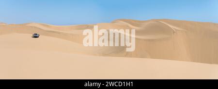 Paysage avec des touristes et 4x4 sur les dunes près de la rive atlantique du désert de Naukluft, tourné dans la lumière brillante de la fin du printemps à Walvis Bay, Namibie, Afrique Banque D'Images