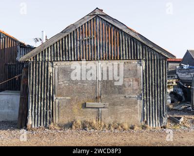 Bâtiment délabré en panneaux ondulés rouillés, avec de vieilles portes en panneaux de bois. Southwold Harbour, Suffolk. ROYAUME-UNI Banque D'Images