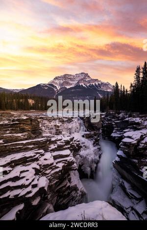 Une image de photographie de paysage d'art des chutes Athabasca dans le parc national Jasper après un saupoudrage frais de neige lors d'un coucher de soleil dynamique et vibrant. Banque D'Images