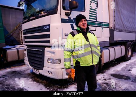 Medyka, Pologne, 15 janvier 2024. Chauffeur de camion se tient devant ses camions alors qu'il attend sur un parking sur l'autoroute A4 pour traverser la frontière polono-ukrainienne alors que la grève du syndicat polonais des transports se poursuit. L'Union exige la renégociation des accords de transport entre l'Ukraine et l'Union européenne. Les manifestants ont bloqué 3 points de passage pour le transport par camion, autorisant seulement 4 camions par heure, à l'exclusion de l'aide humanitaire et militaire et des produits chimiques et alimentaires sensibles. La grève a commencé le 6 novembre. Les conducteurs ukrainiens disent attendre plus de 10 jours, les responsables polonais disent que la file d'attente est de 115 heures. Crédit : Domini Banque D'Images