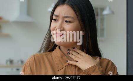 Malade asiatique chinoise toucher mal de gorge mal de cou fille malade perdre la voix souffrant d'allergie coronavirus covid infection amygdales inflammation Banque D'Images