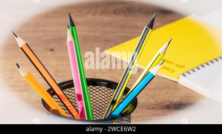 Illuminez votre espace de travail avec cette image accueillante composée de crayons colorés et d'un bloc-notes vierge disposé sur un bureau bien rangé, prêt à l'emploi Banque D'Images