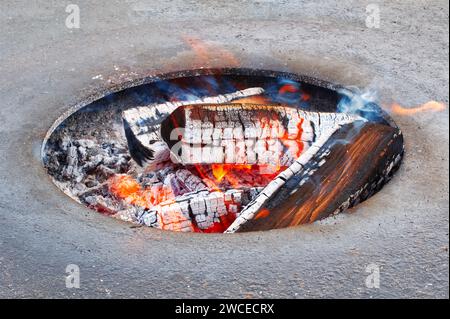 Les flammes se balancent et scintillent, créant des motifs fascinants qui contrastent avec les teintes plus sombres du charbon de bois. Banque D'Images