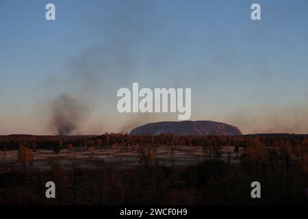 Installation artistique Field of Light (jour) de l'artiste Bruce Munro & Uluru au crépuscule avec fumée de feu d'herbe en Australie centrale Banque D'Images