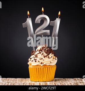 Bougie d'anniversaire numéro 121 - cupcake anniversaire sur fond noir Banque D'Images