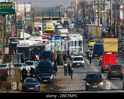Afumati, Roumanie - 15 janvier 2024 : la circulation automobile est légèrement entravée en raison de camions et de tracteurs stationnés sur la route lors de la manifestation des transporteurs et des agriculteurs, dans la commune d'Afumati, à 12 km au nord de Bucarest. Ils protestent dans toute la Roumanie contre les prix élevés des assurances, les taux d’imposition, les longues attentes pour franchir les frontières, exigeant des facilités fiscales, une simplification de la législation, un paiement plus rapide des subventions aux agriculteurs touchés par la sécheresse ou les pertes causées par les importations de céréales en provenance d’Ukraine. Crédit : Lucian Alecu/Alamy Live News Banque D'Images