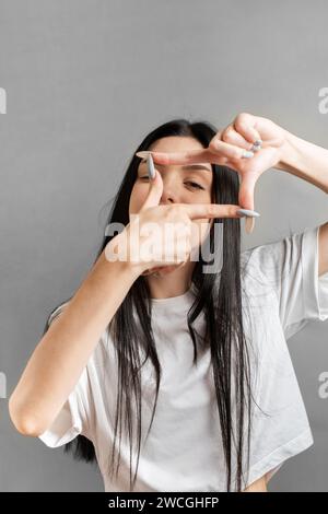 Jeune fille adolescente montre le cadre avec ses mains Banque D'Images