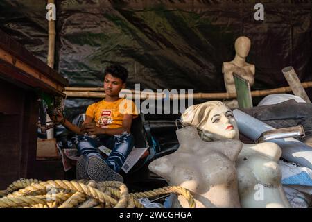 Jaynagar, Inde. 15 janvier 2024. Un vendeur de mannequins est assis à l'intérieur de sa boutique avec son stock pour vendre à une foire de la ferraille au Bengale occidental. Les habitants de Mathurapur Bengale occidental, en Inde, ont observé une bonne pratique de gestion des déchets en organisant une sorte de foire, la «Bhanga Mela» (Une foire des articles de rebut), où ils exposent des objets ménagers usagés et abandonnés à la vente. Des milliers de personnes viennent ici pour acheter ces produits de rebut ou des biens d'occasion pour les utiliser dans leurs maisons. Crédit : SOPA Images Limited/Alamy Live News Banque D'Images