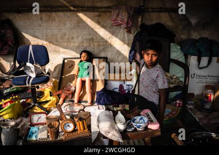 Jaynagar, Inde. 15 janvier 2024. Un petit garçon vend des jouets usagés dans un magasin à l'intérieur d'une foire de la ferraille au Bengale occidental. Les habitants de Mathurapur Bengale occidental, en Inde, ont observé une bonne pratique de gestion des déchets en organisant une sorte de foire, la «Bhanga Mela» (Une foire des articles de rebut), où ils exposent des objets ménagers usagés et abandonnés à la vente. Des milliers de personnes viennent ici pour acheter ces produits de rebut ou des biens d'occasion pour les utiliser dans leurs maisons. Crédit : SOPA Images Limited/Alamy Live News Banque D'Images