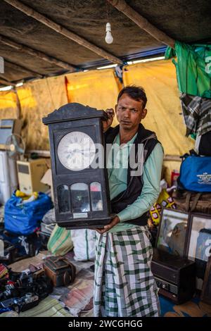 Jaynagar, Inde. 14 janvier 2024. Un scrappeur montre son stock d'une horloge murale à l'intérieur de son magasin à une foire de la ferraille au Bengale occidental. Les habitants de Mathurapur Bengale occidental, en Inde, ont observé une bonne pratique de gestion des déchets en organisant une sorte de foire, la «Bhanga Mela» (Une foire des articles de rebut), où ils exposent des objets ménagers usagés et abandonnés à la vente. Des milliers de personnes viennent ici pour acheter ces produits de rebut ou des biens d'occasion pour les utiliser dans leurs maisons. Crédit : SOPA Images Limited/Alamy Live News Banque D'Images