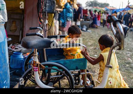 Jaynagar, Inde. 15 janvier 2024. Un enfant est assis dans un fauteuil roulant d'occasion tout en jouant dans une foire d'occasion au Bengale occidental. Les habitants de Mathurapur Bengale occidental, en Inde, ont observé une bonne pratique de gestion des déchets en organisant une sorte de foire, la «Bhanga Mela» (Une foire des articles de rebut), où ils exposent des objets ménagers usagés et abandonnés à la vente. Des milliers de personnes viennent ici pour acheter ces produits de rebut ou des biens d'occasion pour les utiliser dans leurs maisons. Crédit : SOPA Images Limited/Alamy Live News Banque D'Images