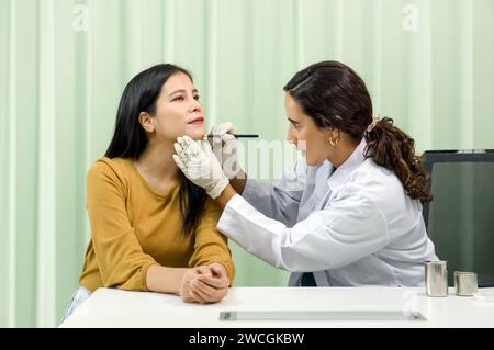 Un professionnel de la santé effectue précisément une procédure de diagnostic du menton sur une patiente dans un environnement clinique désinfecté. Ils ont Banque D'Images