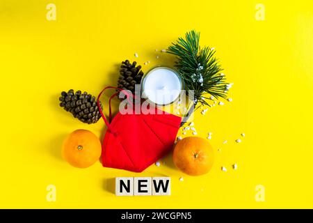 Mandarines reposent dans le masque médical parmi les branches de l'arbre de Noël, mot nouveaux cubes en bois Banque D'Images