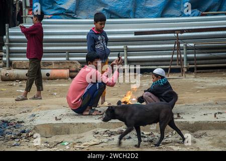 Au milieu du froid hivernal, les gens de la rue se rassemblent autour d'un feu scintillant, jouant avec des mélodies hivernales émouvantes. Cette image a été prise le 13 janvier 2024 Banque D'Images