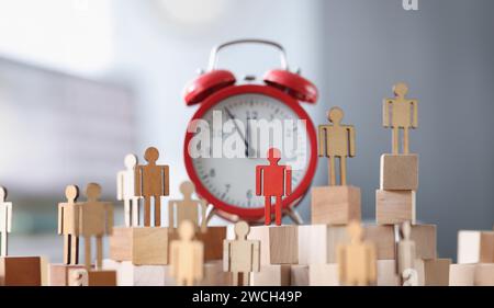 Figurines en bois avec un support rouge à côté de l'alarme horloge Banque D'Images