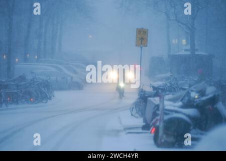 Hambourg, Allemagne. 16 janvier 2024. Un cycliste roule sur une route enneigée. L'hiver est de retour en Allemagne. La neige fraîche et les routes verglacées ont entraîné plusieurs accidents. Le tout clair pour les routes glacées n'est pas en vue pour le moment. Crédit : Marcus Brandt/dpa/Alamy Live News Banque D'Images