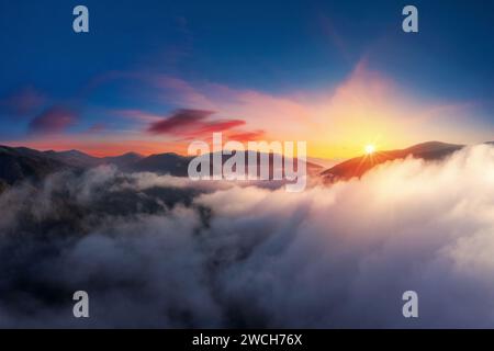 Coucher de soleil spectaculaire haut dans les montagnes au-dessus des nuages de vue aérienne. Banque D'Images