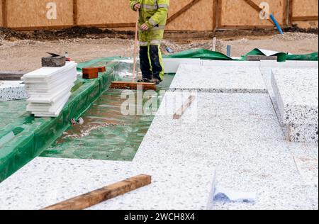 Constructeur plaçant des panneaux isolants de polystyrène sur la membrane d'étanchéité pendant la construction de plancher. Concept d'économie d'énergie Banque D'Images