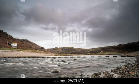 Tremplins, traversant une rivière, avec le château de Pennard, en arrière-plan. L'emplacement est la Three Cliffs Bay, dans la péninsule de Gower, au pays de Galles Banque D'Images