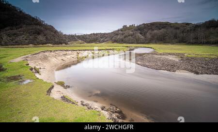 Une rivière fluide, située dans Three Cliffs Bay, au pays de Galles, avec le château de Pennard surplombant une colline lointaine Banque D'Images