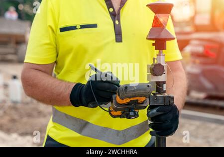 Ingénieur de site utilisant un ordinateur de contrôleur de tablette robuste pour faire fonctionner la station totale EDM pour la mise en place et l'étude en gros plan Banque D'Images