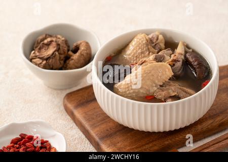 Délicieuse soupe de poulet aux champignons shiitake take taïwanais dans un bol sur fond de table blanc. Banque D'Images