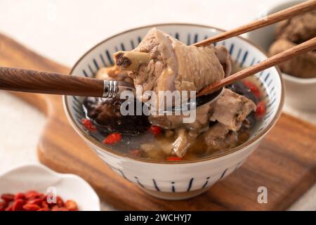 Délicieuse soupe de poulet aux champignons shiitake take taïwanais dans un bol sur fond de table blanc. Banque D'Images