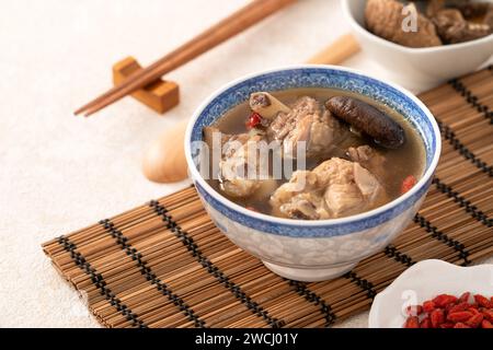 Délicieuse soupe de poulet aux champignons shiitake take taïwanais dans un bol sur fond de table blanc. Banque D'Images