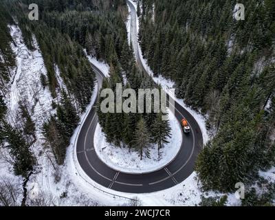 Eibenstock, Allemagne. 16 janvier 2024. Un camion traverse un virage serpentin sur une route de campagne dans les Monts Ore. Après de légères chutes de neige au début de la semaine, la quantité de neige augmentera presque à l'échelle nationale à partir de mercredi. Des tempêtes et des perturbations majeures sont possibles. Le service météorologique allemand (DWD) à Offenbach a averti d'une «situation de tempête complète» pour mercredi. (Vue aérienne avec un drone) crédit : Jan Woitas/dpa/Alamy Live News Banque D'Images