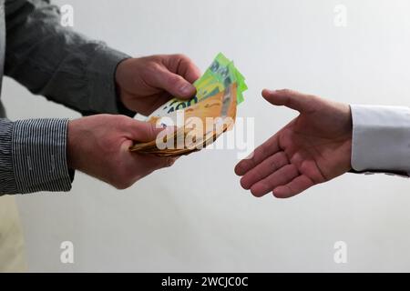 deux gars se serrent la main et blanchissent de l'argent, des pots-de-vin possibles ou de la corruption - fond blanc. Banque D'Images