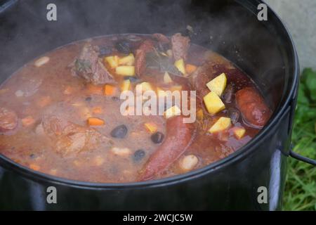 goulash de haricot cuit sur un feu ouvert dans un grand chaudron à l'air libre. Banque D'Images