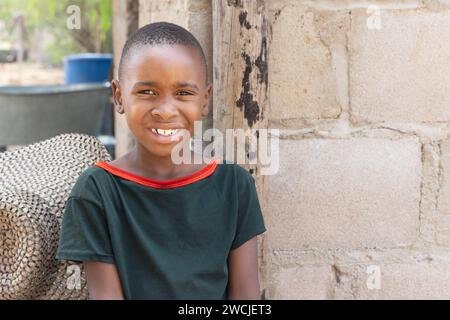 portrait jeune enfant africain dans le village, un chapeau et la maison en arrière-plan Banque D'Images