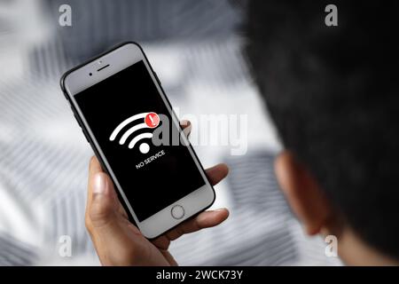 Main masculine tenant un téléphone intelligent avec signe aucun service sur l'écran. Communication, problème cellulaire, concept de mauvaise connexion. Banque D'Images