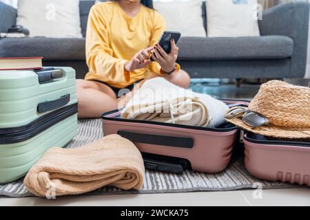 Une jeune femme avec un sac de voyage s'enregistre pour son vol en ligne via son smartphone Banque D'Images