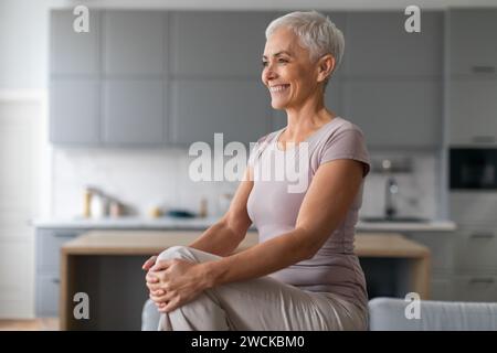 Joyeuse femme mature faisant l'exercice High Knees dans le salon Banque D'Images