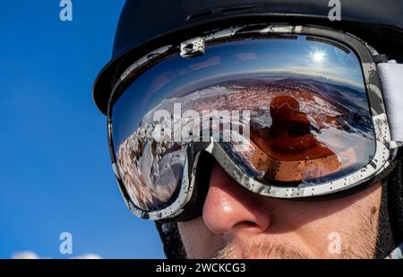 Reflet dans les lunettes de ski gros plan : pistes de montagne enneigées pour le ski. Équipement de skieur ou snowboarder : casque, masque, lunettes sur homme. Activités de week-end Banque D'Images